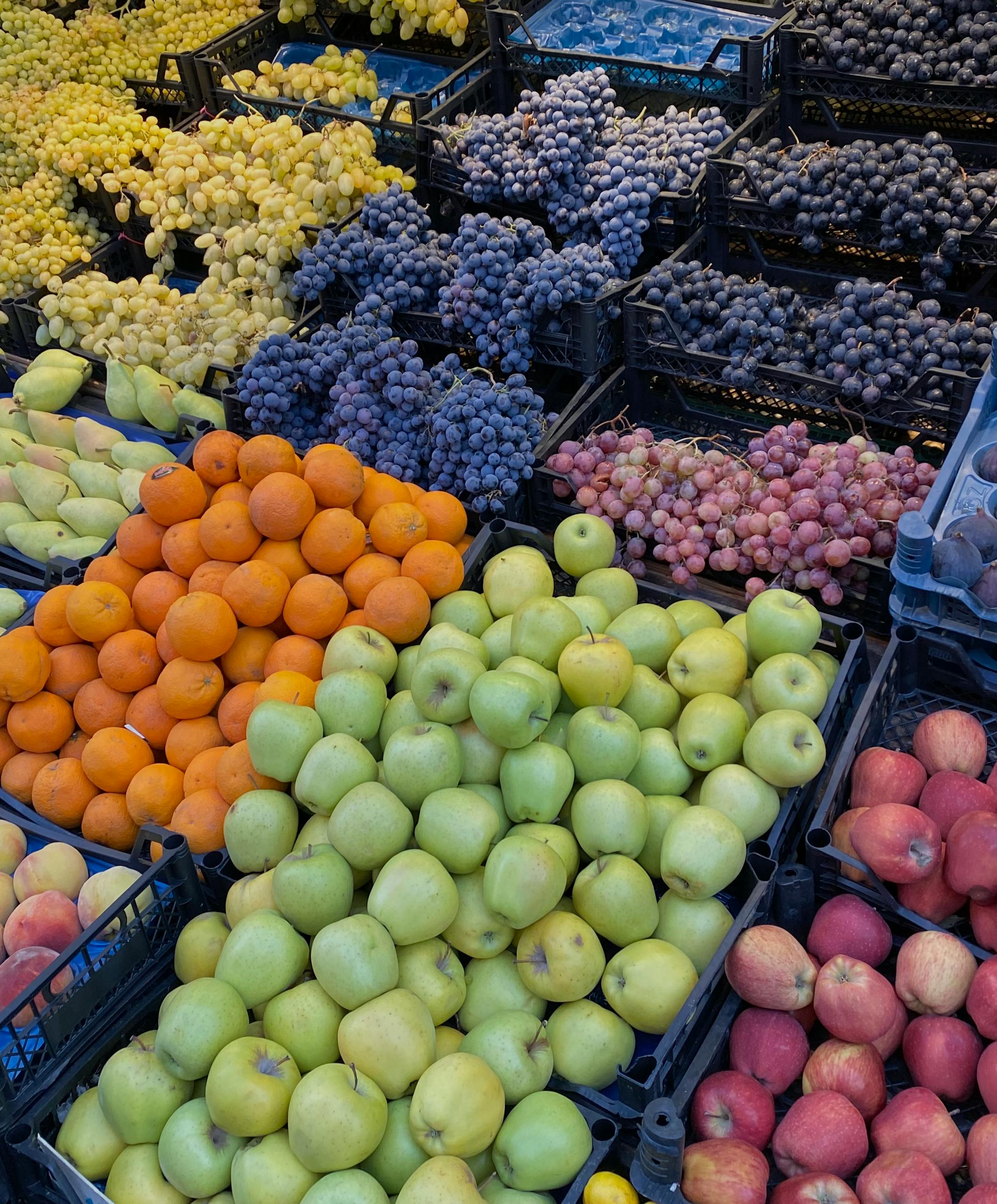 Colorful assortment of fresh fruits in plastic crates at a bustling market.